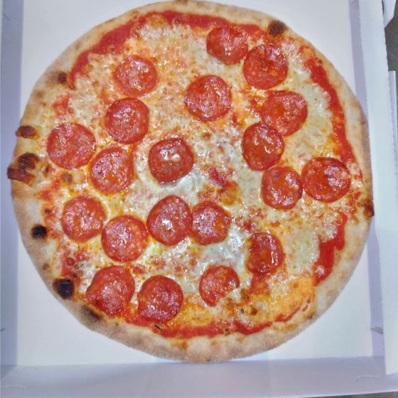 Una pizza con il salamino nel cartone d'asporto aperto