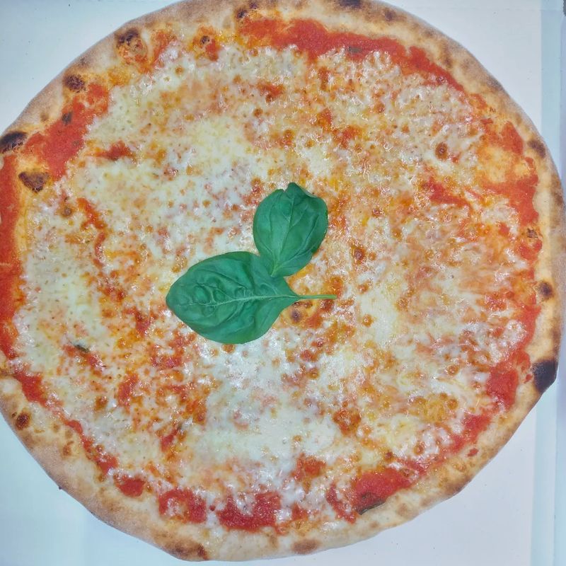Margherita nel cartone d'asporto, con una foglia di basilico al centro